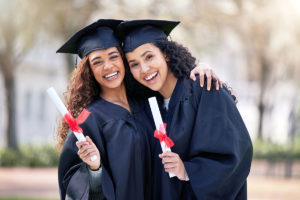 two young women dressed in caps and gowns celebrating graduation