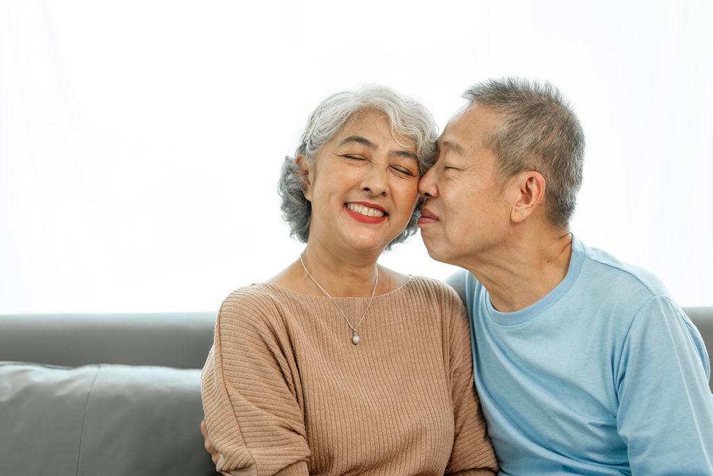 elderly couple sitting together he is snuggling her cheek