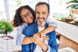middle aged hispanic couple embracing while sitting on a terrace